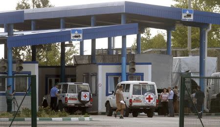 Cars of the Red Cross and trucks of a Russian convoy carrying humanitarian aid for Ukraine are seen at a Russia-Ukraine border crossing point "Donetsk" during a control check in Rostov Region, August 21, 2014. REUTERS/Alexander Demianchuk