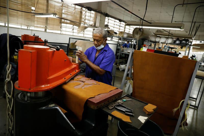 Una trabajadora utiliza maquinaria de corte de cuero en el fabricante de calzado Full Time, en Caracas