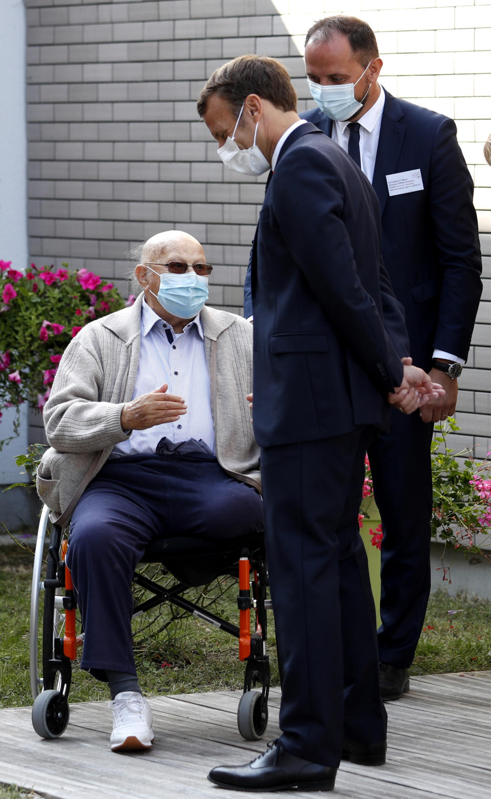 French President Emmanuel Macron, right, talks to a resident at the 'La Bonne Eure' nursing home in Bracieux, central France, Tuesday, Sept. 22, 2020. For the first time in months, virus infections and deaths in French nursing homes are on the rise again. (Yoan Valat/Pool Photo via AP)