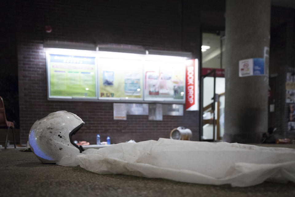 In this Thursday, Nov. 21, 2019, photo, helmet and rain cover are left on the ground of the Hong Kong Polytechnic University in Hong Kong. Most of the protesters who took over the university have left following clashes with police, but an unknown number have remained inside, hoping somehow to avoid arrest. (AP Photo/Vincent Thian)