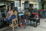 In this May 23, 2019 photo, power generator vendor Juli Barbosa poses for a photo while waiting for customers at the Maracaibo flea market, in Venezuela. The ongoing black outs have led to a scramble for generators by residents and small businesses fearing another big outage could hit without warning, plunging their lives once again into chaos. (AP Photo/Rodrigo Abd)