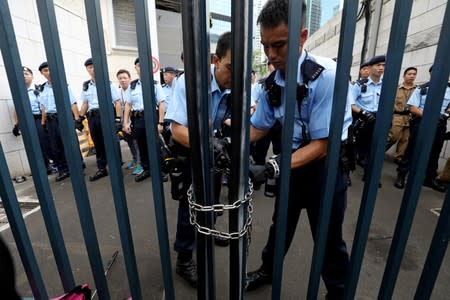 Police officers lock the gate of a police headquarter after protesters attempt to storm in, in Hong Kong