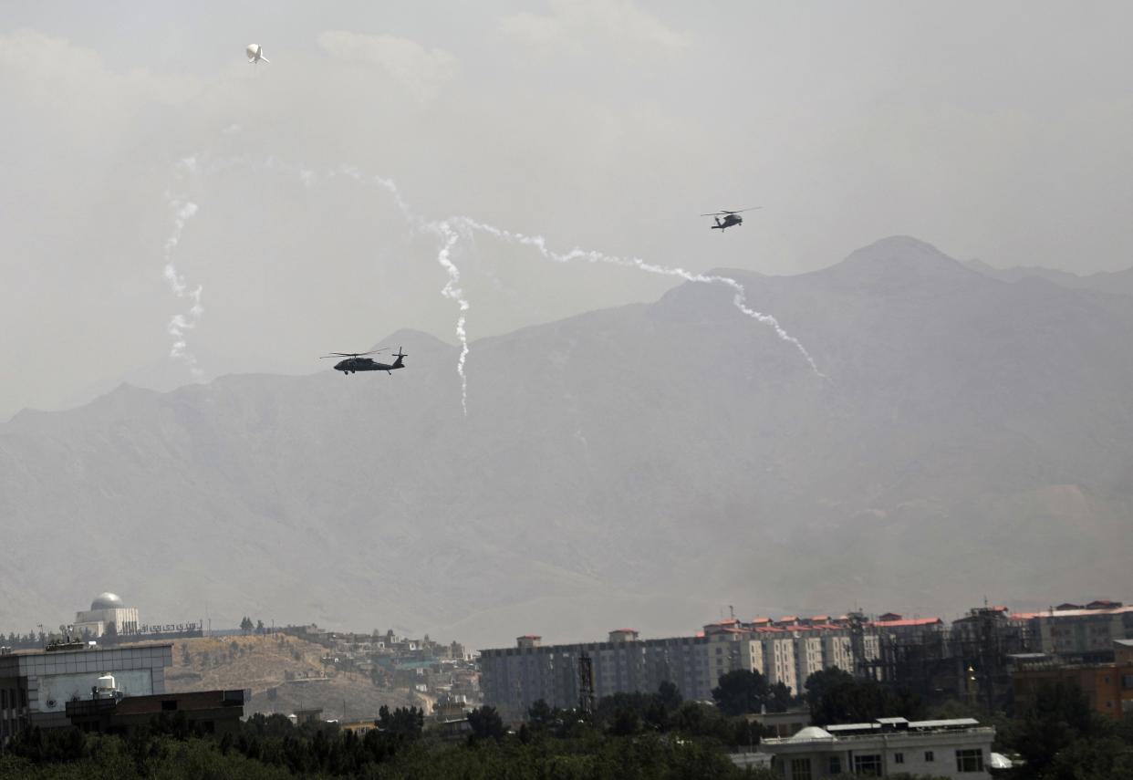 Anti-missile decoy flares are deployed as U.S. Black Hawk military helicopters and a dirigible balloon fly over the city of Kabul, Afghanistan on Sunday, Aug. 15, 2021. Taliban fighters entered the outskirts of the Afghan capital on Sunday and said they were awaiting a "peaceful transfer" of the city after promising not to take it by force, but amid the uncertainty, panicked workers fled government offices and helicopters landed at the U.S. Embassy.