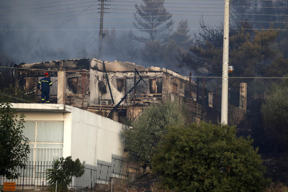 A firefighter observes a damaged house during a wildfire in Peania, eastern Athens, Monday, Aug. 12, 2019. A big fire broke out in the Athens suburb of Peania east of the city, and authorities ordered the evacuation of nearby houses. (AP Photo/Thanassis Stavrakis)