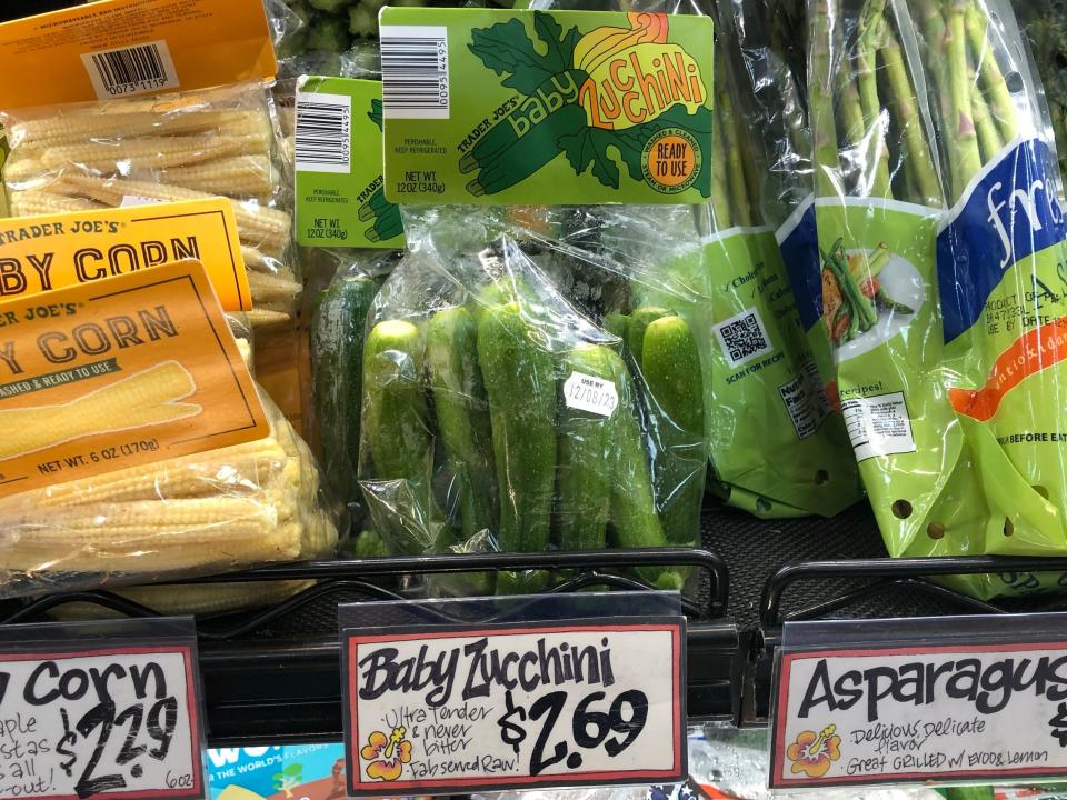 A display of fresh vegetables at Trader Joe's, including baby zucchini with a price tag that reads $2.69.
