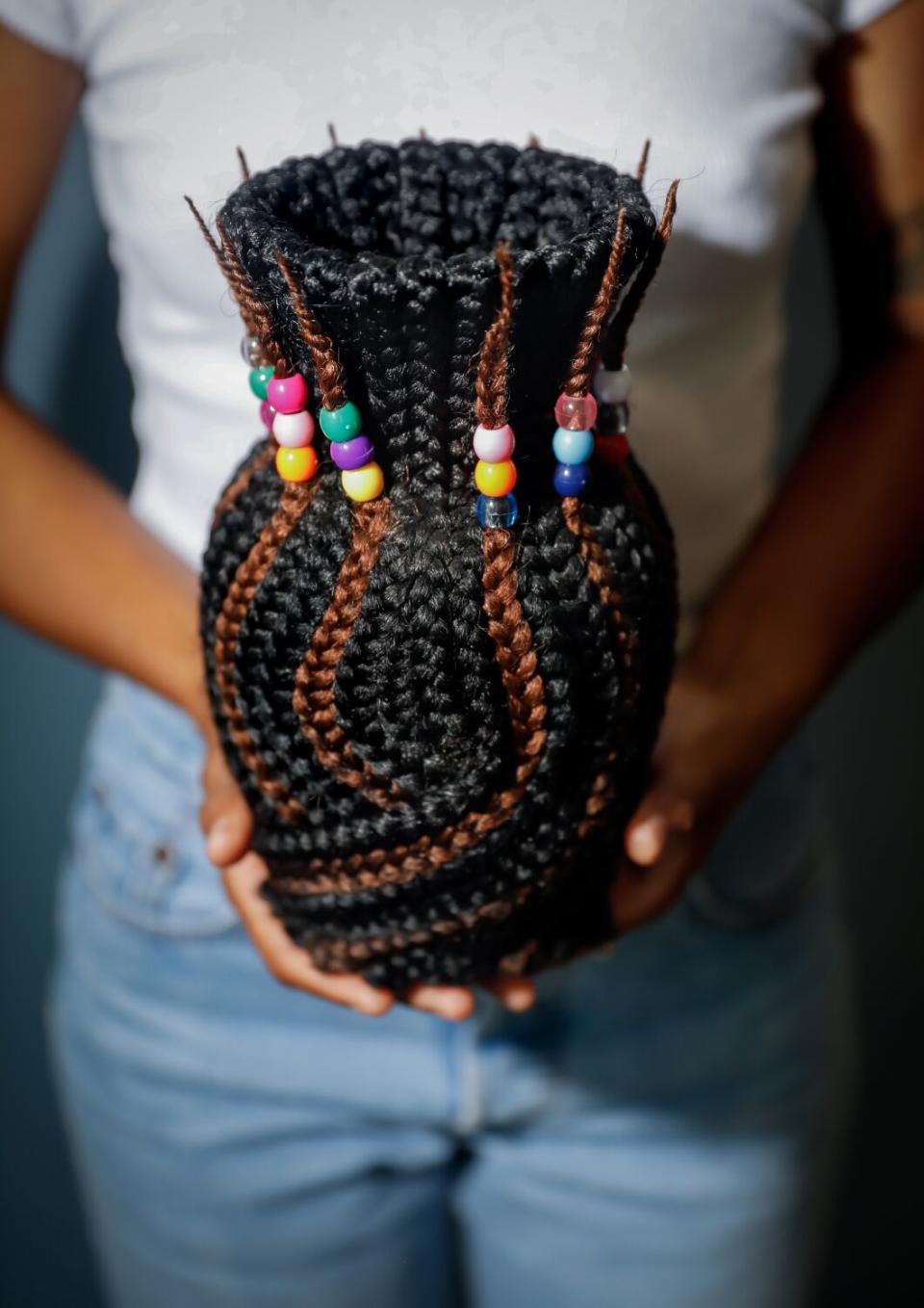 Artist Dana Davenport holds a vase made of box braids