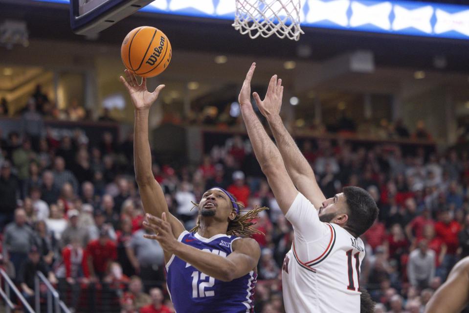 TCU's Xavier Cork (12) shoots over Texas Tech's Fardaws Aimaq (11) during the second half of an NCAA college basketball game, Saturday, Feb. 25, 2023, in Lubbock, Texas. (AP Photo/Chase Seabolt)