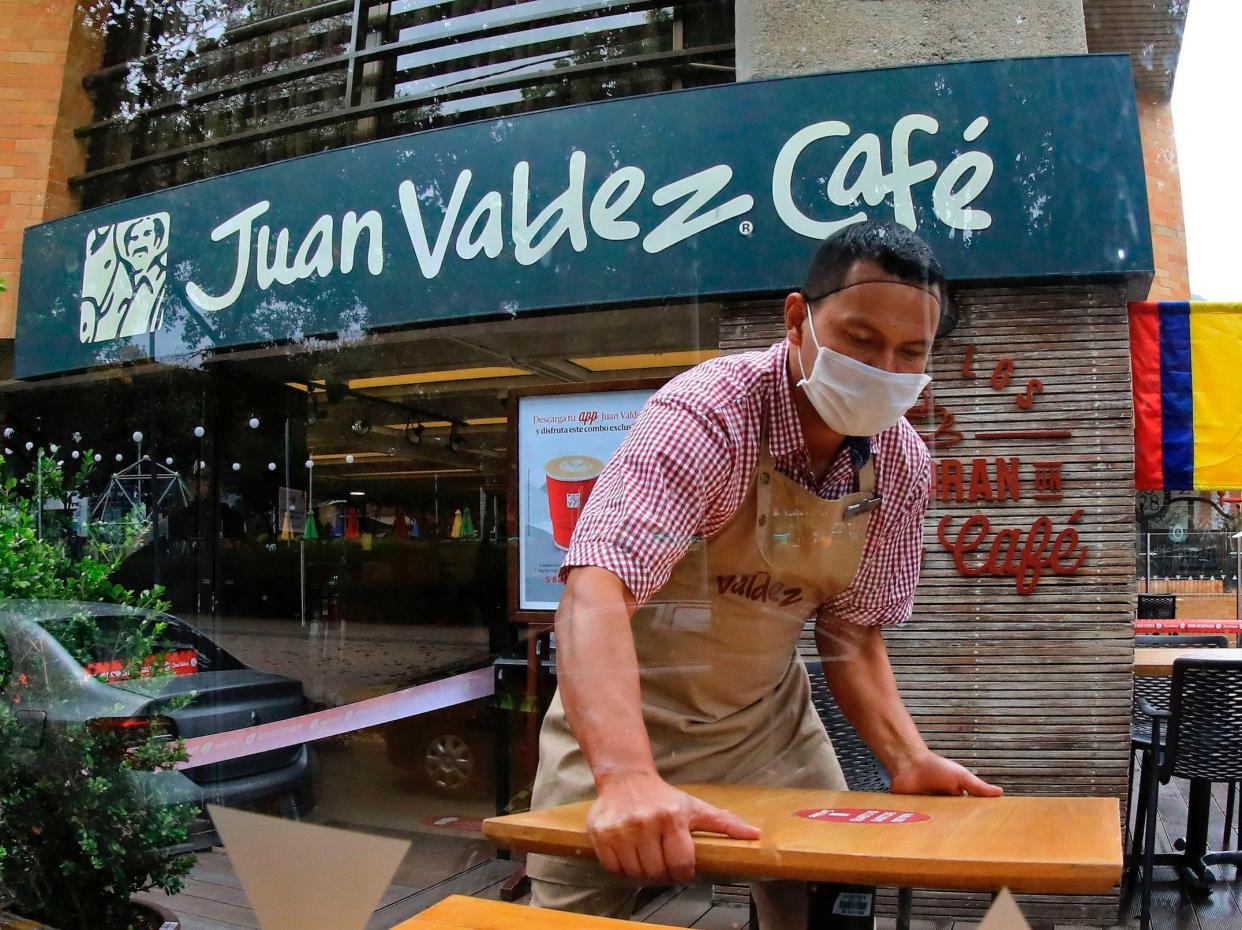 An employee prepares the terrace of a coffee shop to reopen in Bogota on August 14, 2020, amid the new coronavirus pandemic. - Bogota's Mayor Claudia Lopez authorized some passenger flights at El Dorado International Airport and will allow restaurants with outdoor seating to reopen from September 1. (Photo by DANIEL MUNOZ / AFP) (Photo by )
