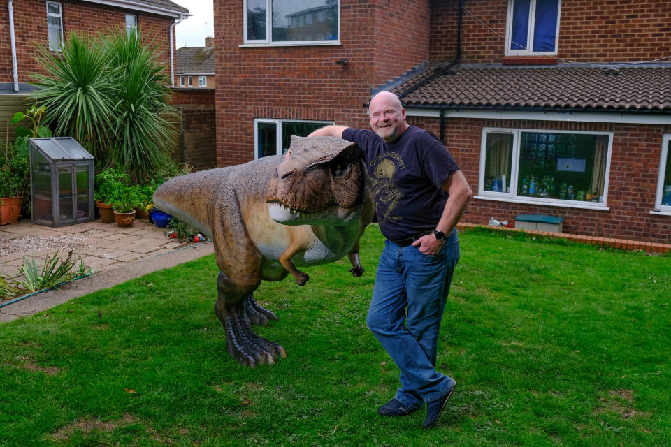 A wacky husband shocked his wife who wanted to brighten up their garden with a gnome - by installing a 12ft-tall replica of a T-REX on the patio. Adrian Shaw, 52, snapped up the 14-stone resin and fiberglass dinosaur and hired a crane to winch it into position on Thursday (3/9). He came up with the madcap-scheme after wife Deborah, 53, begged him to clean up the back garden of their home in Leamington Spa, Warks. The IT analyst paid £1,600 for the replica of the terrifying beast, which he named ‘Dave’ and put it on the patio.