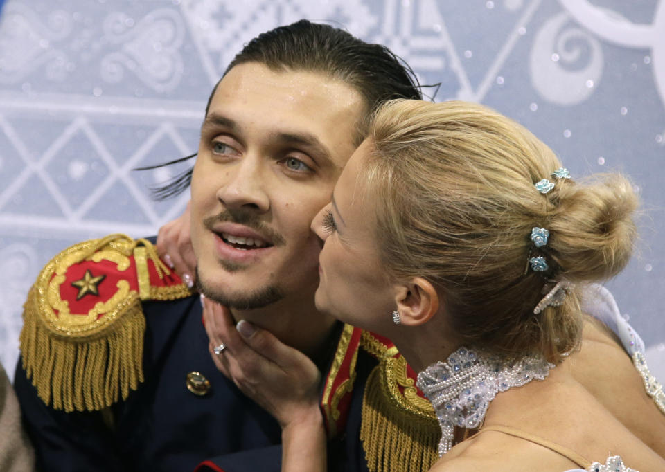 Tatiana Volosozhar kisses Maxim Trankov of Russia as they sit in the results area after competing in the pairs short program figure skating competition at the Iceberg Skating Palace during the 2014 Winter Olympics, Tuesday, Feb. 11, 2014, in Sochi, Russia. (AP Photo/Darron Cummings)