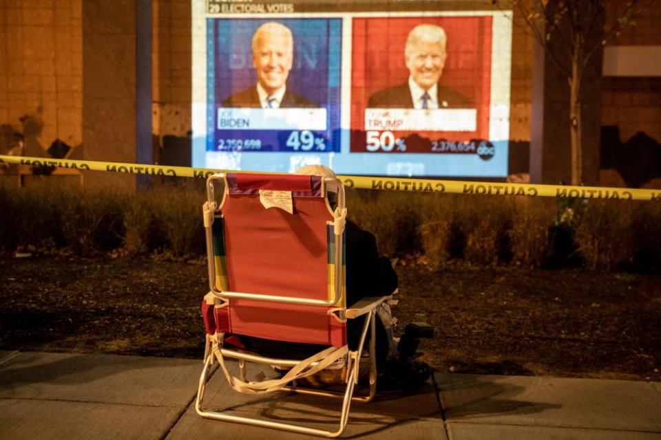 A person watches a screen showing early voting results at Black Lives Matter Plaza on 3 November in Washington DC.