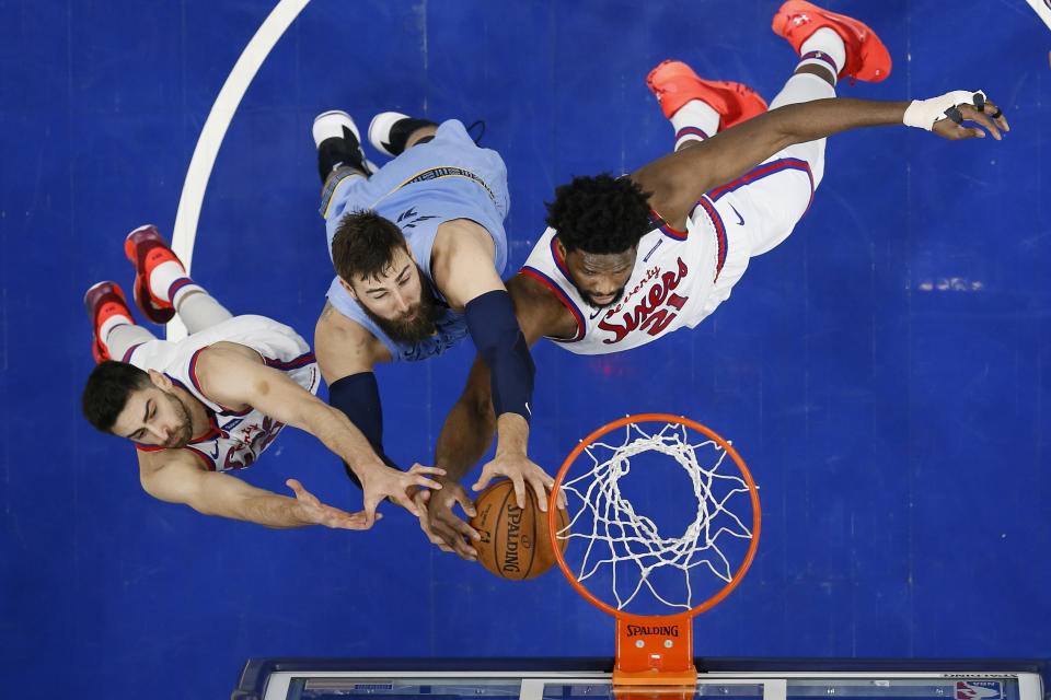 Memphis Grizzlies' Jonas Valanciunas, center, leaps for a rebound between Philadelphia 76ers' Furkan Korkmaz, left, and Joel Embiid during the first half of an NBA basketball game Friday, Feb. 7, 2020, in Philadelphia. (AP Photo/Matt Slocum)