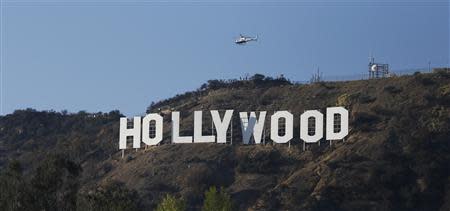 A Los Angeles Police Department (LAPD) helicopter flies over the Hollywood sign in Hollywood, California February 21, 2014. REUTERS/Mario Anzuoni