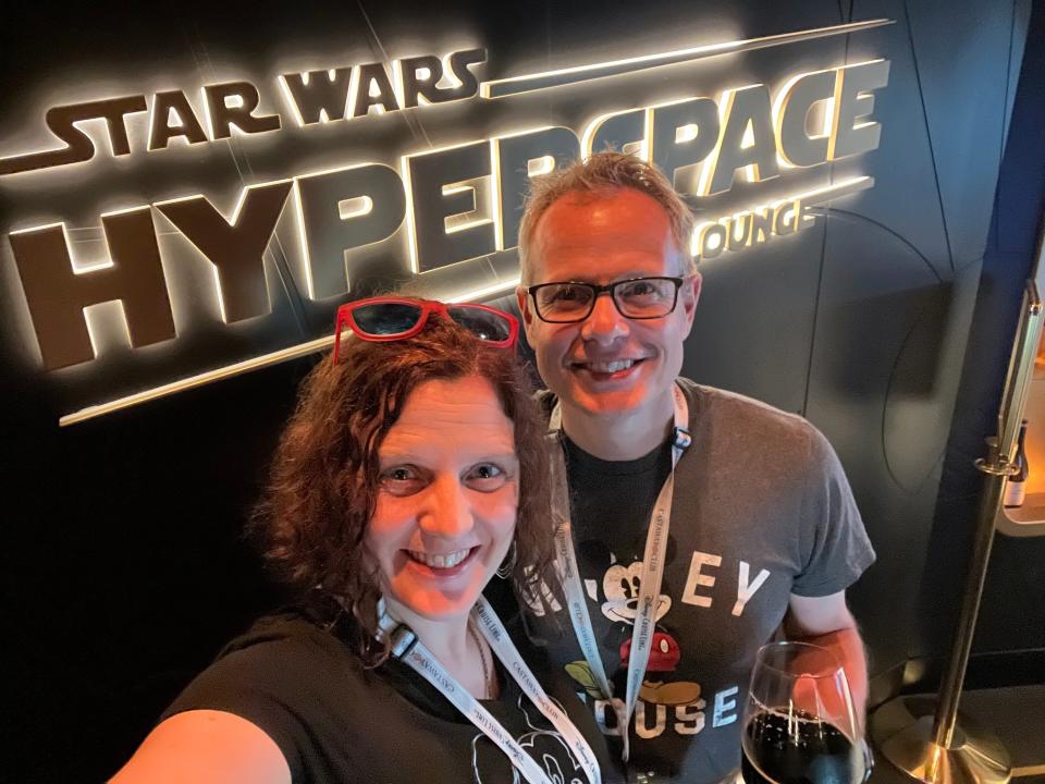 kari and her husband posing in front of the star wars hyperspace lounge on the disney wish