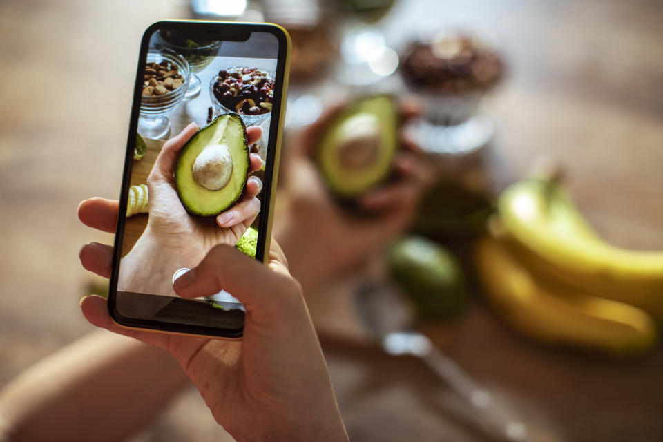 A person taking a photo of an avocado.