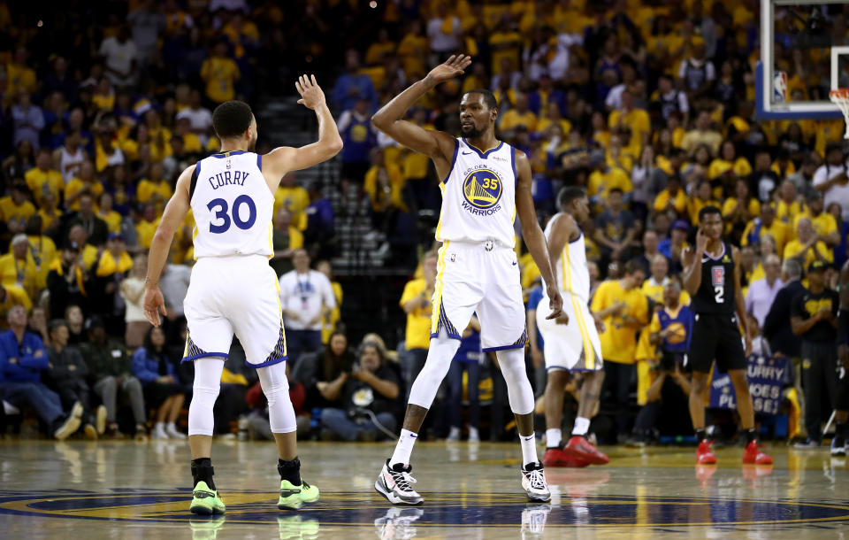OAKLAND, CALIFORNIA - APRIL 13:  Stephen Curry #30 high fives Kevin Durant #35 of the Golden State Warriors during their game against the LA Clippers during Game One of the first round of the 2019 NBA Western Conference Playoffs at ORACLE Arena on April 13, 2019 in Oakland, California. NOTE TO USER: User expressly acknowledges and agrees that, by downloading and or using this photograph, User is consenting to the terms and conditions of the Getty Images License Agreement. (Photo by Ezra Shaw/Getty Images)