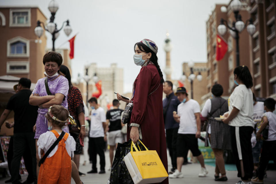 People with face masks walk on the street of Xinjiang. 