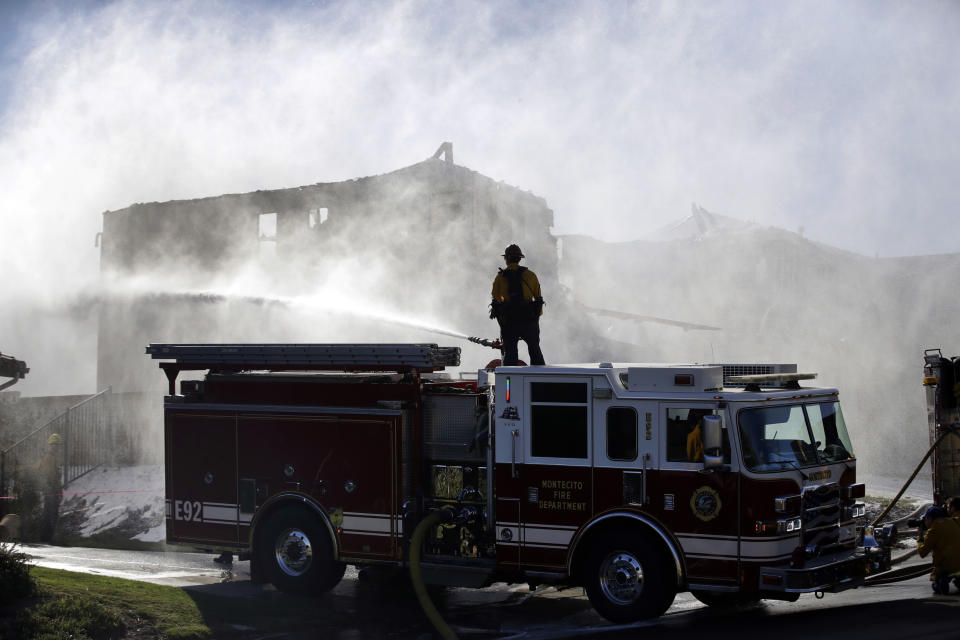 A firefighter tries to put out a residence fire caused by a wildfire from atop a fire truck Friday, Oct. 25, 2019, in Santa Clarita, Calif. An estimated 50,000 people were under evacuation orders in the Santa Clarita area north of Los Angeles as hot, dry Santa Ana winds howling at up to 50 mph (80 kph) drove the flames into neighborhoods(AP Photo/Marcio Jose Sanchez)