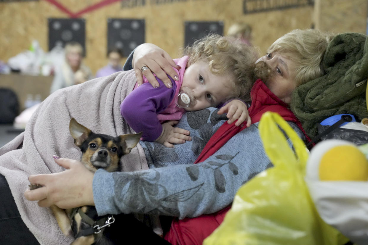 A women holds a child and a dog in a shelter inside a building in Mariupol, Ukraine, Sunday, Feb. 27, 2022. (Evgeniy Maloletka/AP)
