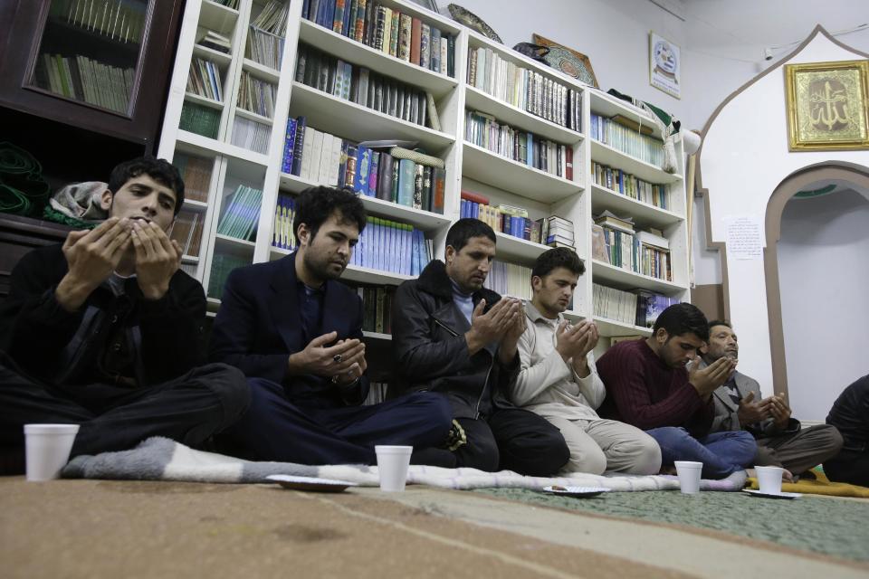 Survivors of a boat sinking pray at a makeshift basement mosque in western Athens on Friday, Jan. 24, 2014. Twelve people, mostly children, are believed to have perished in Monday's sinking. Only two bodies have been found. Greece's merchant marine minister said Friday the survivors of a fatal migrant boat sinking changed their accounts of the incident, initially saying the Greek Coast Guard saved them but later accusing it of badly mishandling the rescue operation. (AP Photo/Thanassis Stavrakis)