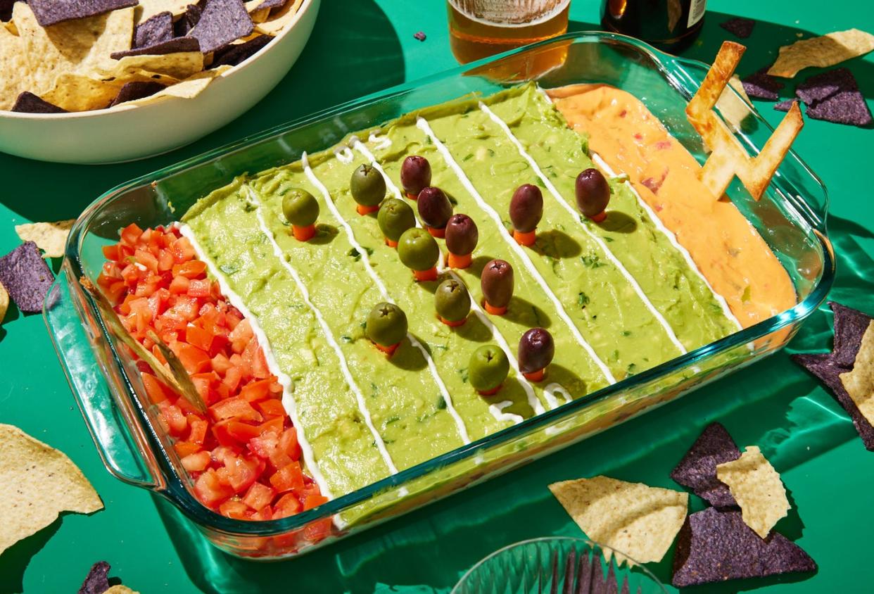 football field decorated layered dip with refried beans, sour cream, pico de gallo, guacamole, and queso