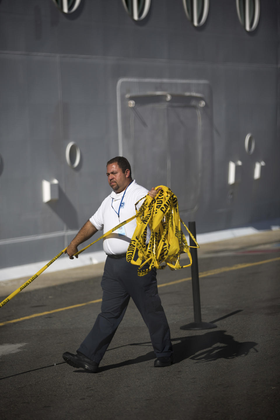 A West Indian Company employee removes a yellow caution barricade tape from around the Royal Caribbean International's Explorer of the Seas crusie ship, docked at Charlotte Amalie Harbor in St. Thomas, United States Virgin Islands, Sunday, Jan. 26, 2014. U.S. health officials have boarded the cruise ship to investigate an illness outbreak that has stricken at least 300 people with gastrointestinal symptoms including vomiting and diarrhea. (AP Photo/Thomas Layer)