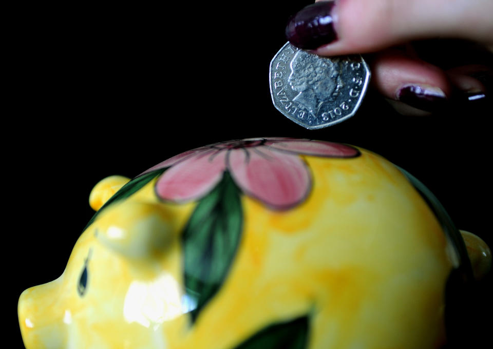 A young girl puts a coin in a piggy bank.   (Photo by Nick Ansell/PA Images via Getty Images)