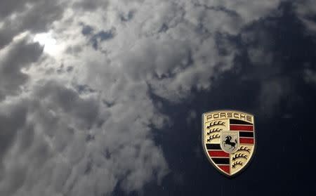 Clouds are reflected beside a logo of German car manufacturer Porsche on the bonnet of a sports car outside the Porsche museum in Stuttgart July 20, 2009. REUTERS/Johannes Eisele