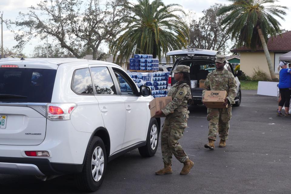 Members of the National Guard based in Jacksonville deliver MRE boxes to a vehicle Monday afternoon at a relief station hosted at San Pedro Catholic Church.