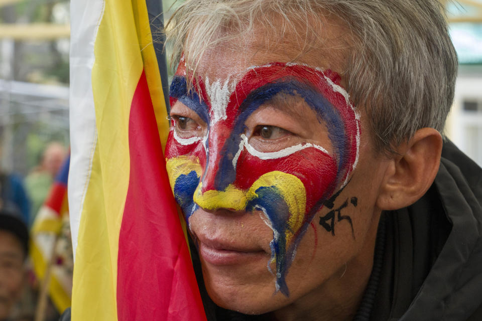 An exile Tibetan with his face painted in the colors of the Tibetan flag listens to a speaker before joining a march to commemorate the 1959 uprising in Tibet on this day, in Dharamshala, India, Sunday, March 10, 2024. (AP Photo/Ashwini Bhatia)