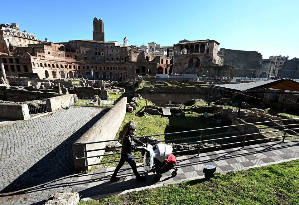 A man pushes a pram as he walks along the Foro Traiano Roman ruins in Rome on March 12, 2020 in Rome, as Italy shut all stores except for pharmacies and food shops in a desperate bid to halt the spread of a coronavirus that has killed 827 in the the country in just over two weeks. (Photo by Vincenzo PINTO / AFP) (Photo by VINCENZO PINTO/AFP via Getty Images)