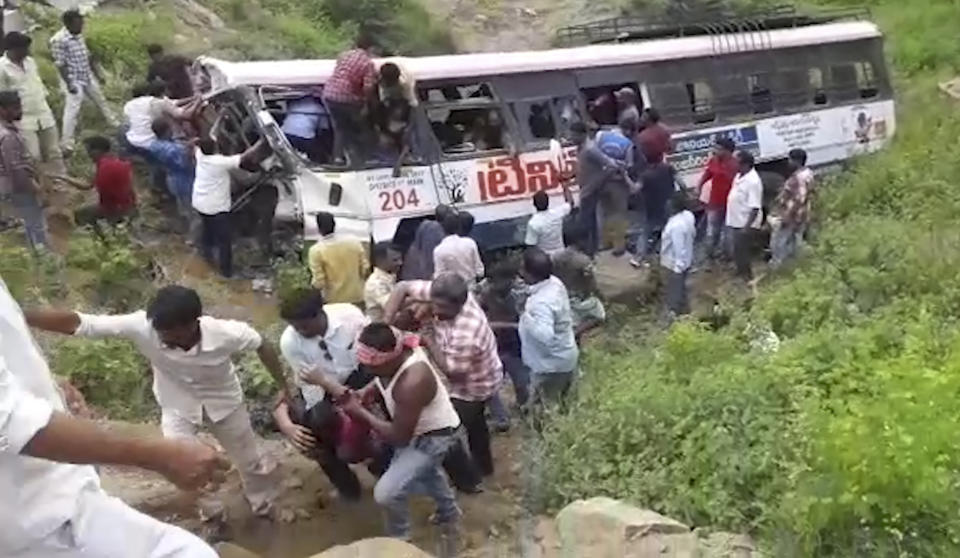 In this grab made from video provided by KK Productions, rescuers pull out passengers from a bus that fell into a gorge in Jagtiyal district of Telangana, India, Tuesday, Sept. 11, 2018. The bus was carrying pilgrims from a Hindu temple in the hills of south India when it plunged off a road killing several people (KK Production via AP)