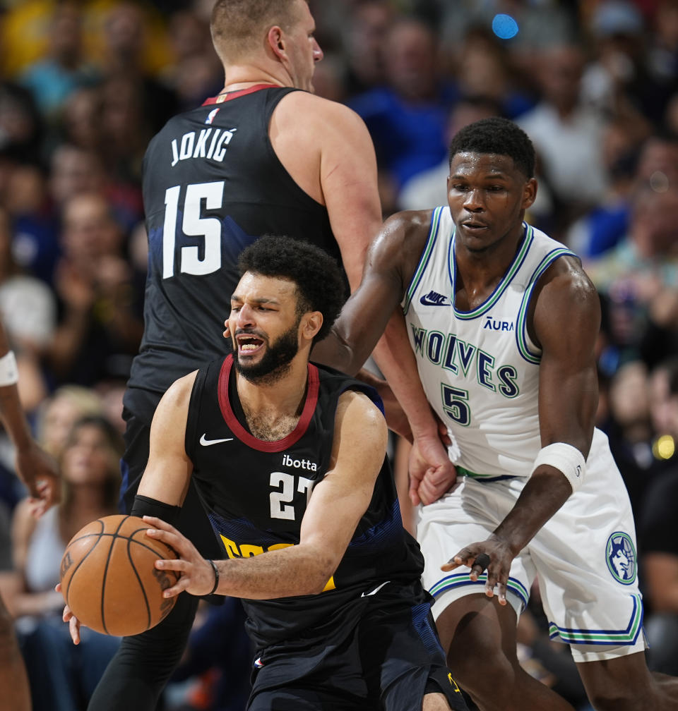 Denver Nuggets guard Jamal Murray, front, fields a pass as center Nikola Jokic, back left, sets a pick on Minnesota Timberwolves guard Anthony Edwards in the second half of Game 7 of an NBA second-round playoff series Sunday, May 19, 2024, in Denver. (AP Photo/David Zalubowski)