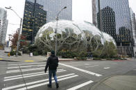 A pedestrian walks near the Amazon Spheres on the company's corporate campus in downtown Seattle, Tuesday, Dec. 7, 2021. Amazon Web Services suffered a major outage Tuesday, the company said, disrupting access to many popular sites. The company provides cloud computing services to many governments, universities and companies, including The Associated Press. (AP Photo/Ted S. Warren)