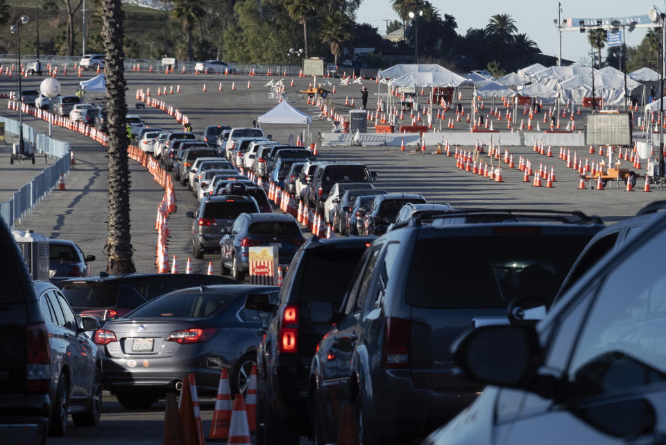 Los Angeles residents wait in line in their cars to receive a covid-19 vaccine at Dodger Stadium, Tuesday, Jan. 26, 2021, in Los Angeles. California is revamping its vaccine delivery system to give the state more control over who gets the shots following intense criticism of a slow and scattered rollout by counties. (AP Photo/Richard Vogel)