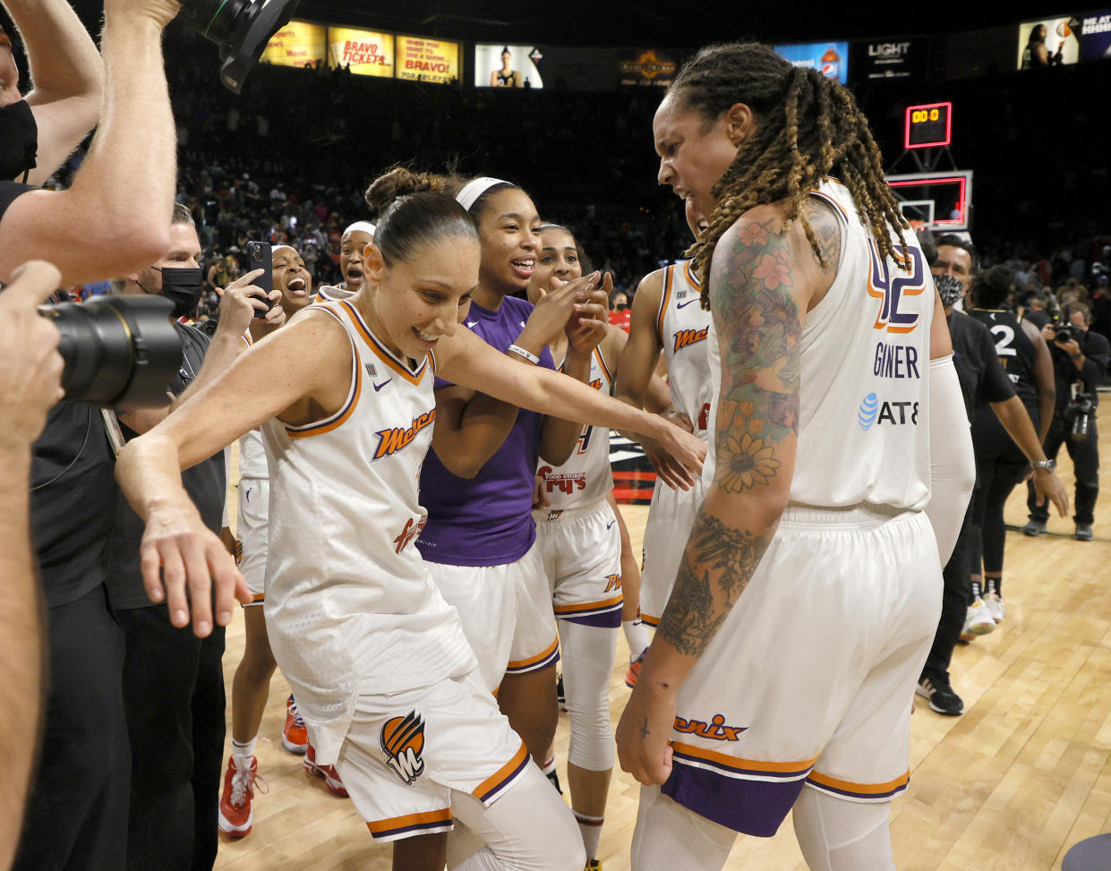 Diana Taurasi falls backward while celebrating with Brittney Griner, who is yelling in excitement, after the Mercury won Game 5 of the WNBA semifinals series against the Aces.