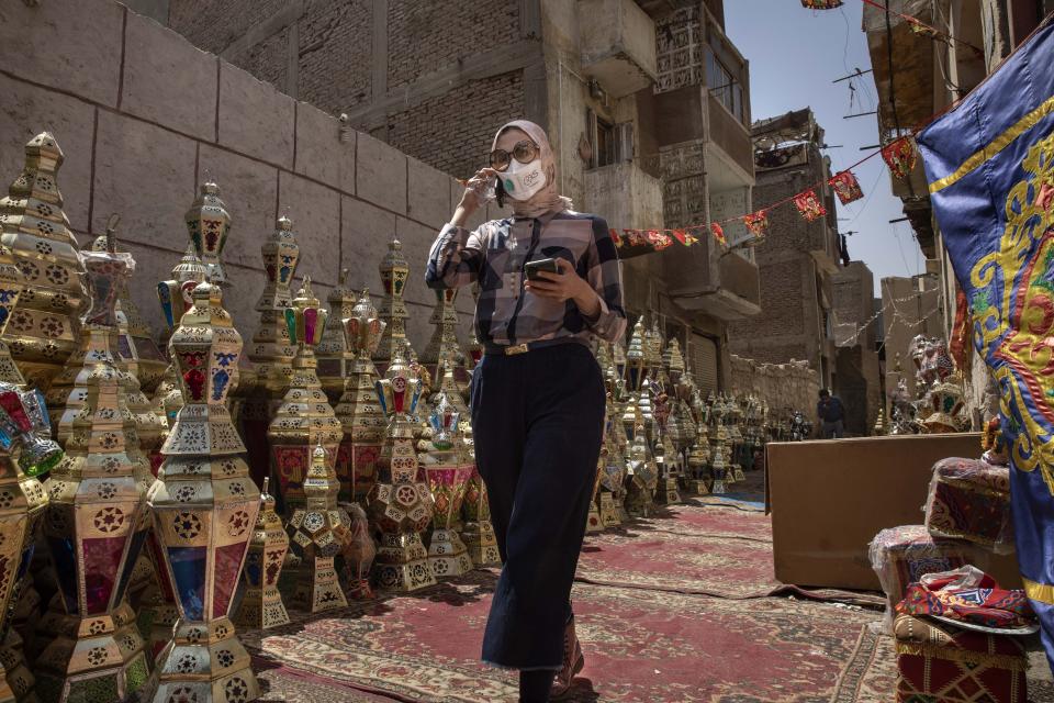 A woman speaks on her phone as she shops for Ramadan lanterns ahead of the holy month, in the Sayeda Zeinab neighborhood of Cairo, Egypt, Tuesday, April 21, 2020. Ramadan begins with the new moon later this week and Muslims all around the world are trying to work out how to maintain the many cherished rituals of Islam's holiest month during the coronavirus pandemic. (AP Photo/Nariman El-Mofty)