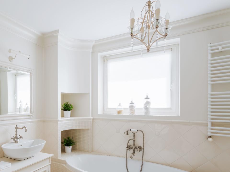 A bathtub with a chandelier hanging over it