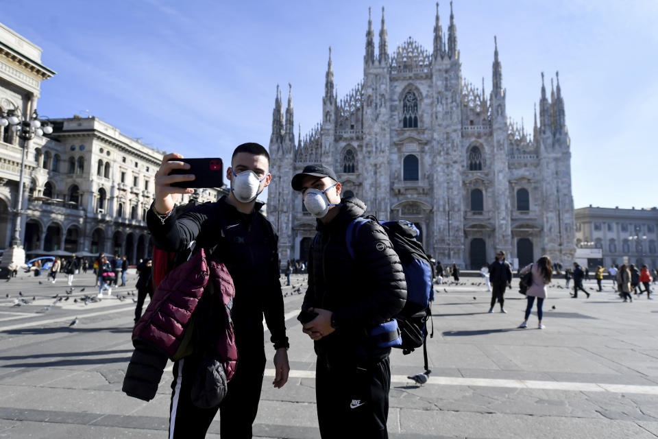 People wearing sanitary masks take a selfie in front of the Duomo gothic cathedral, in Milan, Italy, Monday, Feb. 24, 2020. At least 190 people in Italy’s north have tested positive for the COVID-19 virus and four people have died, including an 84-year-old man who died overnight in Bergamo, the Lombardy regional government reported. (Claudio Furlan/Lapresse via AP)