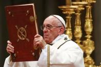 Pope Francis holds the book of the gospels as he leads the Christmas night Mass in Saint Peter's Basilica at the Vatican December 24, 2016. REUTERS/Tony Gentile