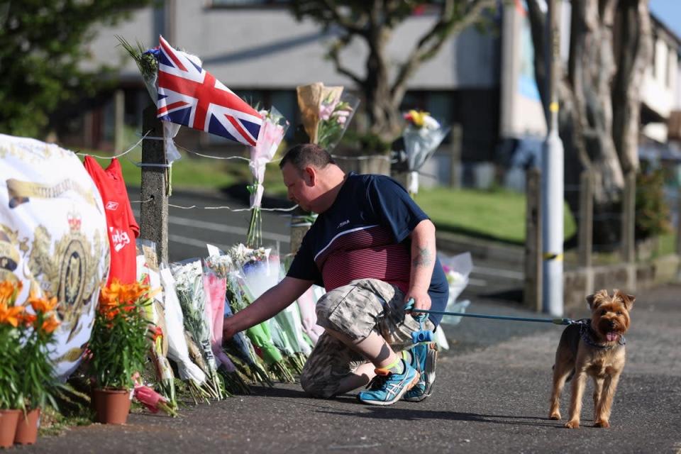 A man lays flowers near the scene after a man died after falling from a bonfire on the Antiville estate in Larne, Co Antrim on Saturday night. Police and ambulance personnel attended the scene after the fatal incident, which happened just after 9.30pm. Picture date: Sunday July 10, 2022 (Liam McBurney/PA) (PA Wire)