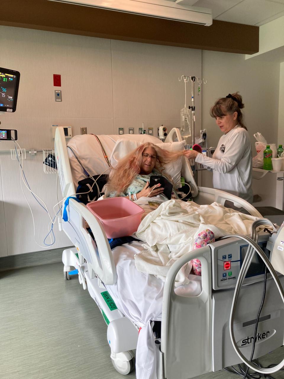 Carrie Williams brushes the hair of friend Diane Medina in an undated photo from a Toledo hospital following the April 20 fatal car crash into the Swan Boat Club in Newport where Medina was injured.