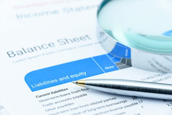 Balance sheet with a magnifying glass and pen