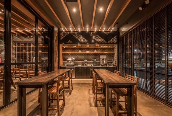 An empty Starbucks store with wood tables and floor-to-ceiling glass windows on the sides