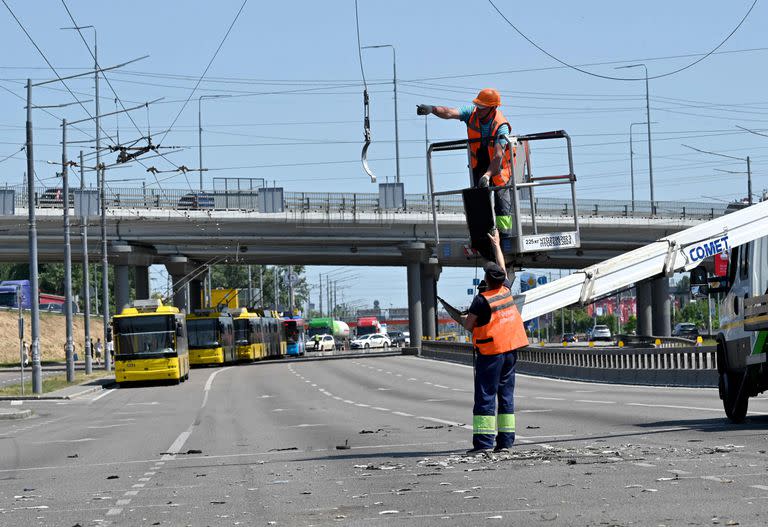 Trabajadores municipales reparan cables eléctricos que resultaron dañados en un inusual ataque diurno dirigido a la capital ucraniana el 29 de mayo de 2023.