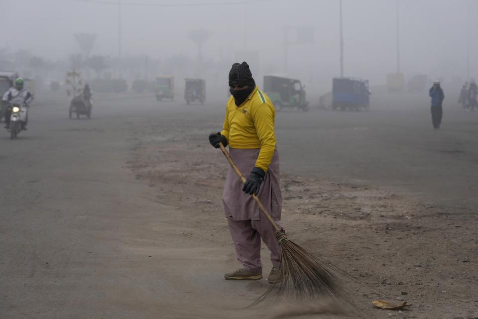 A sweeper cleans an area as smog envelops the area and reduces visibility in Lahore, Pakistan, Thursday, Jan. 11, 2024. Toxic smog has sickened tens of thousands of people in recent months. (AP Photo/K.M. Chaudary)