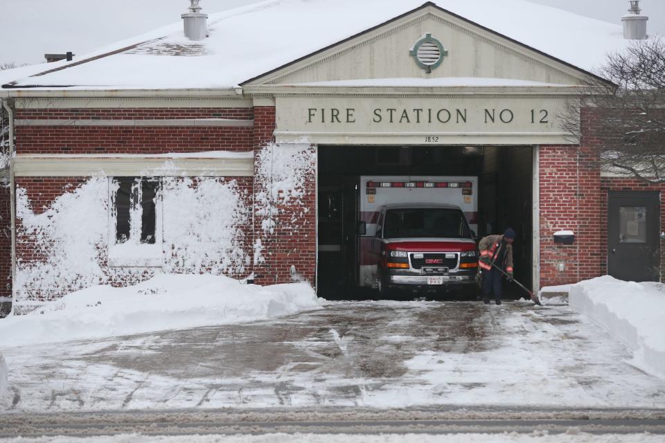A firefighter clears the snow in front of Station Number 12 on West Market Street in Akron.