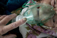 An elderly woman, a patient with coronavirus, breaths with an oxygen mask inside a hospital in Pochaiv, Ukraine, May 1, 2020. (AP Photo/Evgeniy Maloletka)