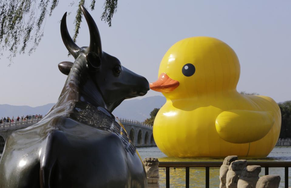 The inflated Rubber Duck by Dutch conceptual artist Florentijn Hofman floats near the Bronze Ox statue, cast in 1755 during the Qing Dynasty, at the Summer Palace in Beijing October 24, 2013. The Rubber Duck will be deflated on October 27 at the Summer Palace, ending its tour in Beijing. The event organizer said over three million visitors have viewed the duck during the past month. (REUTERS/Jason Lee)