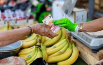 FILE PHOTO: A shopper pays with a ten Euro bank note at a local market in Nice